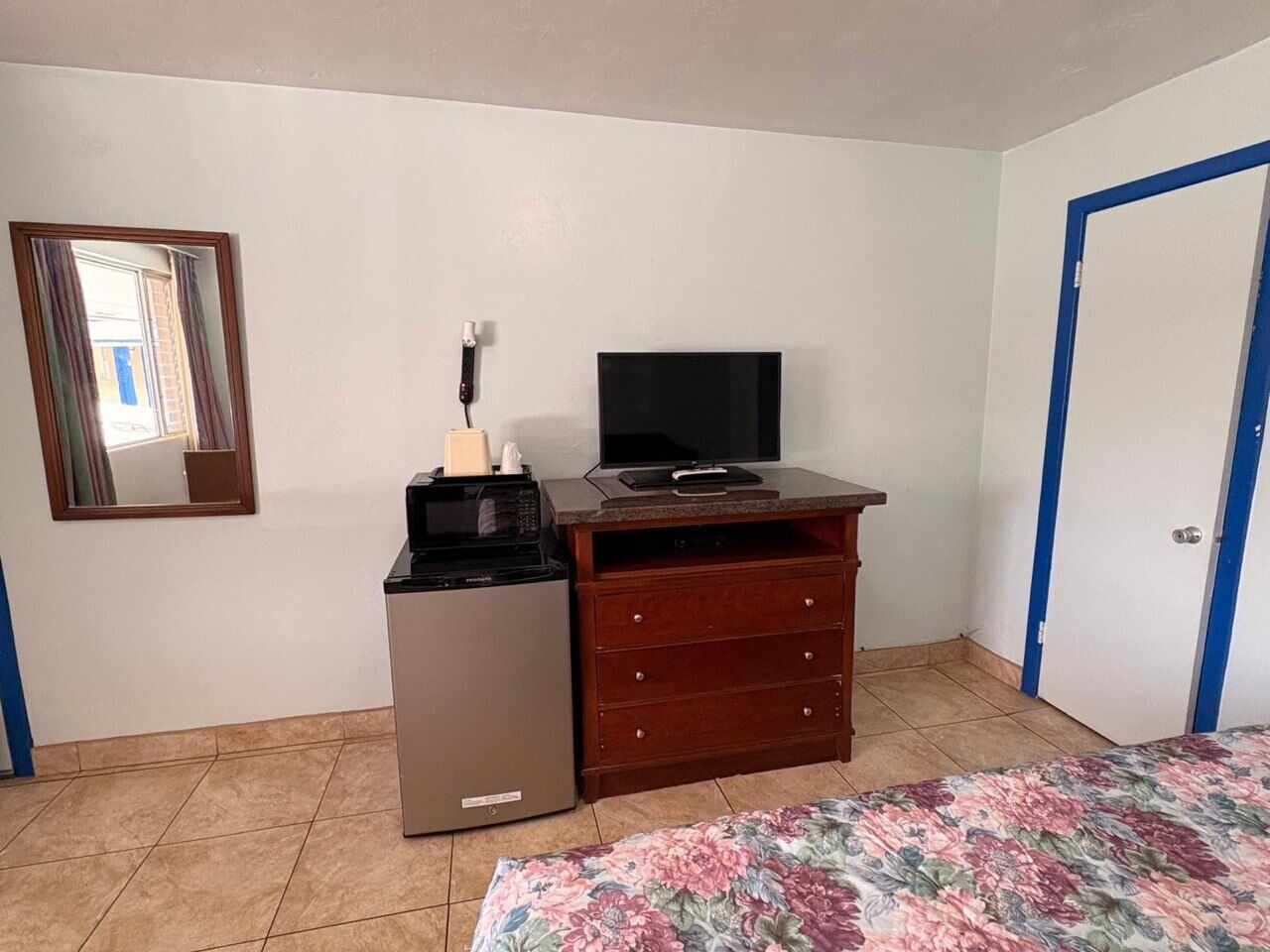 A room with a bed, a dresser, a television, and a refrigerator.