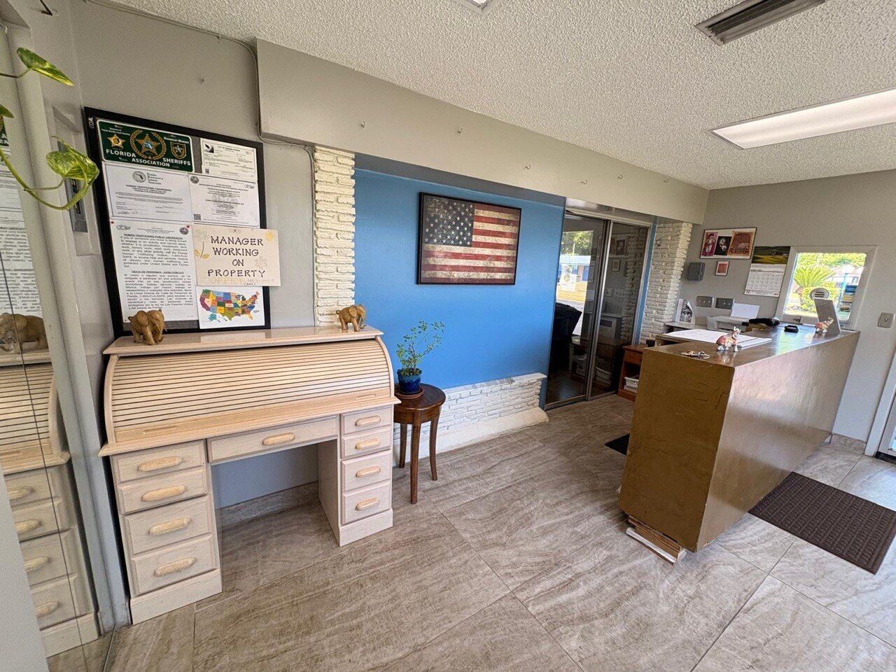 A reception area with a desk, a small table with a plant, and an American flag on the wall.