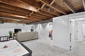 Un espace intérieur comprenant une table de baby-foot, un canapé et un téléviseur en arrière-plan.