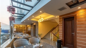 A modern interior with a glass ceiling, a staircase, and a dining area with tables and chairs. - Apex Business Hotel (Kathmandu)