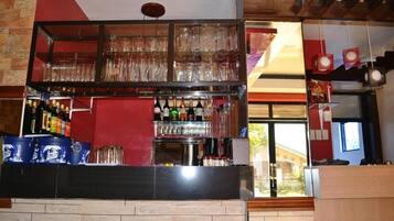A bar area with shelves of bottles and glasses, a counter, and a view of the outside.