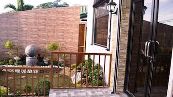 A gated outdoor area with a brick wall, potted plants, and a metal railing.