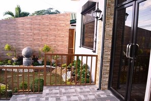 A gated outdoor area with a brick wall, potted plants, and a metal railing. - Casa Del Camba Hotel and Restaurant by Zuzu (Alaminos)