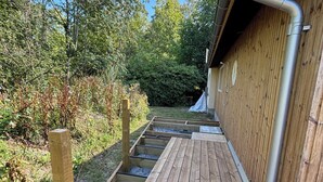 Eine Holzterrasse, die zu einem Gebäude mit einer Metallrinne führt.