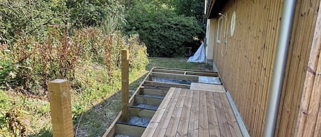 Una terraza de madera que conduce a un edificio con canalón de metal.