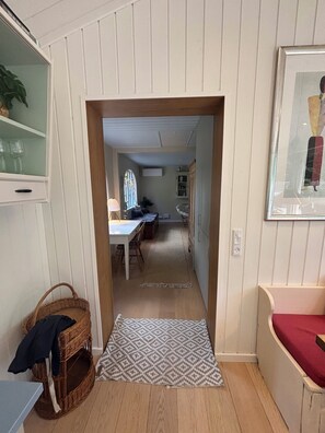 Ein Korridor, der in einen Essbereich führt, mit einem gemusterten Teppich, einem Korbwesen und einem gerahmten Bild an der Wand.