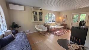 Ein Zimmer mit einem Bett, einem Korbstuhl, einem Sofa, einem kleinen Tisch, einem Schrank und einem Kamin.