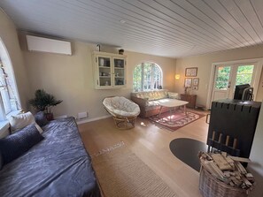 Ein Zimmer mit einem Bett, einem Korbstuhl, einem Sofa, einem kleinen Tisch, einem Schrank und einem Kamin.