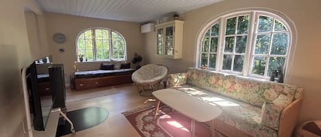 A room with a sofa, a chair, a table, and a window with a view of greenery.