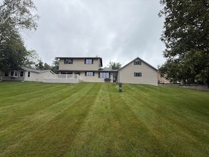 A two-story house with a well-maintained lawn, a front porch, and a small shed.