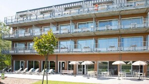 A multi-story hotel with balconies, outdoor seating, and a swimming pool area. - Residence Vacanceole Les Chambres de la Baie (Roz-sur-Couesnon)
