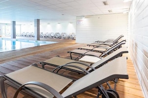 Un área de piscina con tumbonas y una terraza de madera.