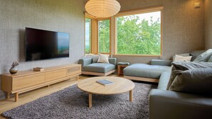 En moderne stue med et fladskærms-tv, en trækommode, et rundt sofabord og to sofaer.