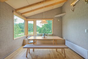 A room with a wooden bench, a table, and a hanging light fixture. - Ume House (Kutchan)