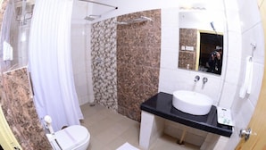 Et badeværelse med brusebad, toilet, vask og spejl.