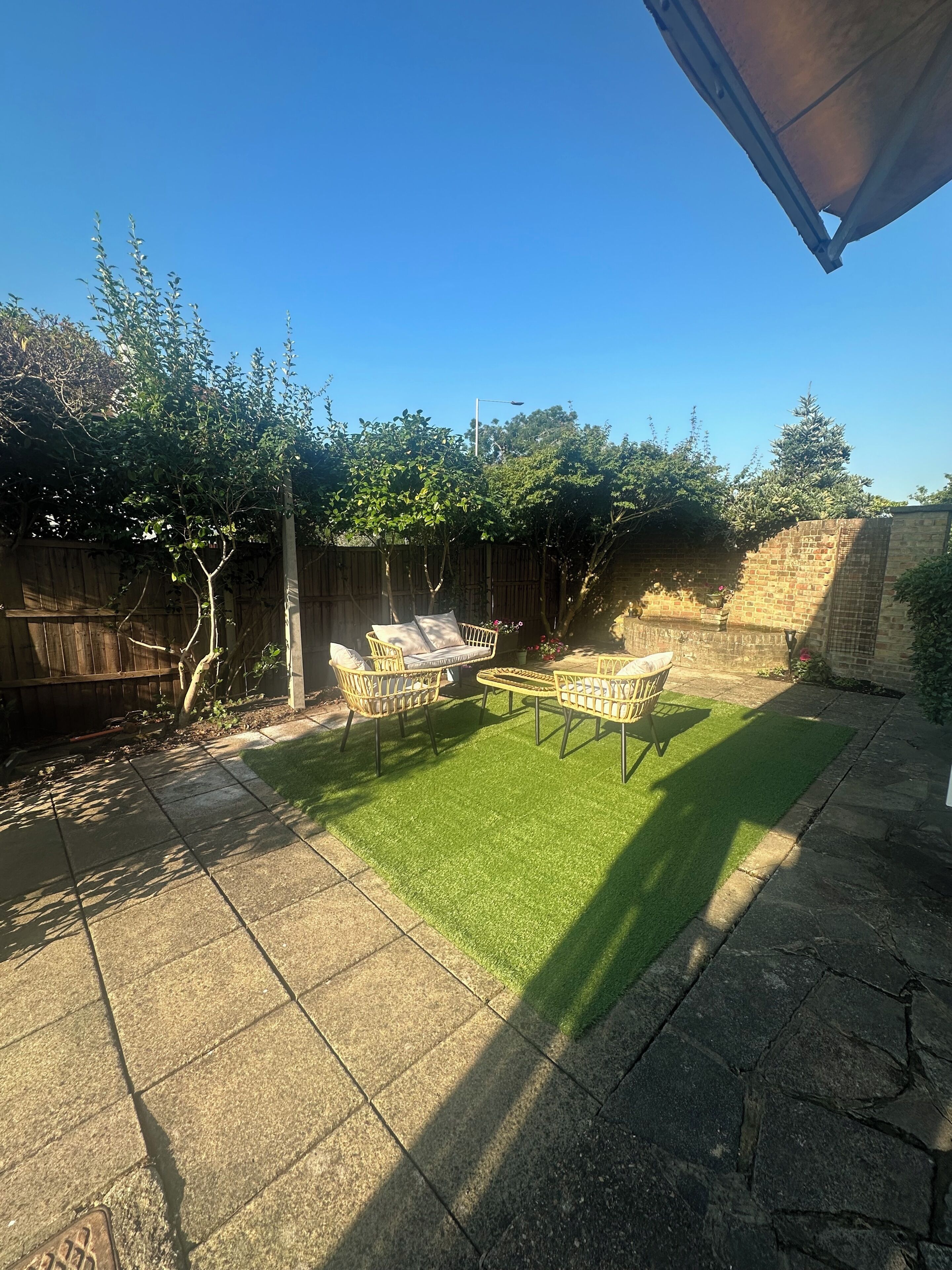 A backyard with a patio area, a wooden fence, and a brick wall.