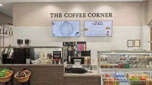 Interieur van een koffiehuis, met een menubord, een kassa en een vitrine met lekkernijen.
