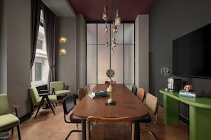 A conference room with a long table, chairs, a projector, and a television. - Moxy Istanbul Beyoglu (Istanbul)