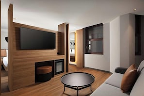 Uma sala de estar moderna com uma televisão de tela plana, uma mesa de centro redonda e um sofá.