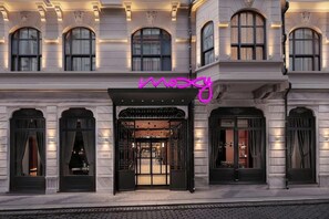 A building facade with a prominent neon sign, large arched windows, and a detailed entrance with a canopy. - Moxy Istanbul Beyoglu (Istanbul)