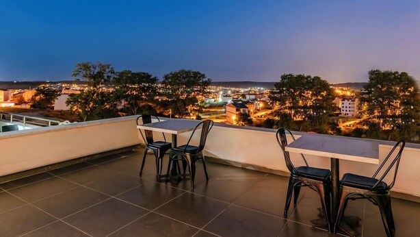 An outdoor terrace with a table and chairs, overlooking a cityscape at dusk. - Hotel Intercity Istanbul Airport (Arnavutköy)