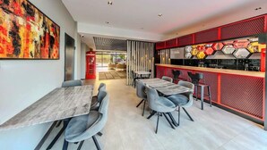 A modern dining area with a bar, seating arrangements, and a large abstract painting on the wall. - Hotel Intercity Istanbul Airport (Arnavutköy)