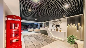 A modern hotel lobby with a red telephone booth, a reception desk, and a large world map on the wall. - Hotel Intercity Istanbul Airport (Arnavutköy)