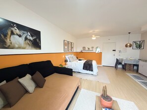 Uma sala moderna com sofá, cama, área de jantar e cozinha.