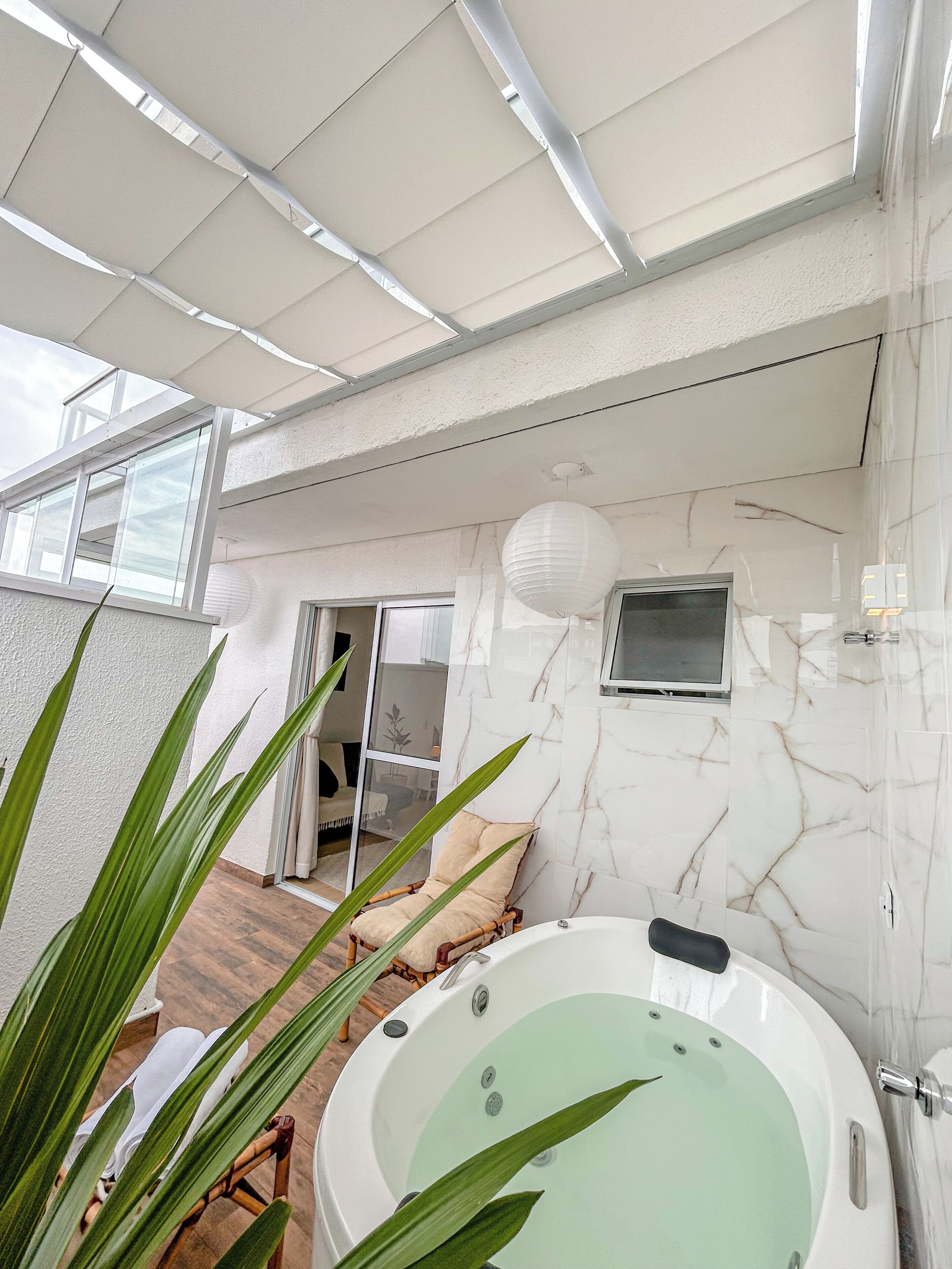 Un baño moderno con pared de mármol, una bañera y un ventanal grande.
