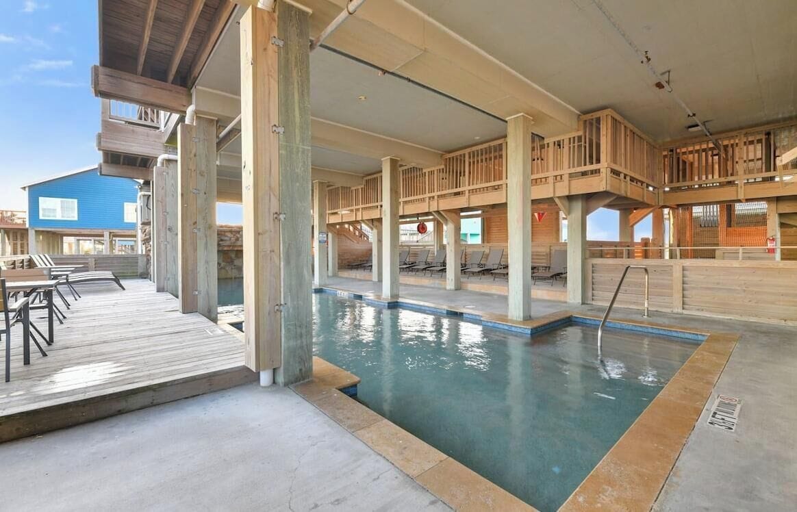 A pool area with wooden deck seating and a clear view of the pool.