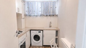 Cocina compacta con lavadora, un comedor pequeño y un radiador.