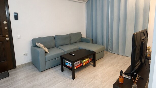 Una sala de estar con un sofá, una mesa de centro con libros, un televisor y un mueble bajo.