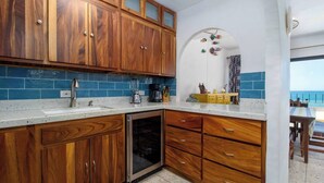 Une cuisine dotée de meubles en bois, d’un lave-vaisselle et d’un plan de travail sur lequel sont disposés divers objets.