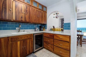 A kitchen with wooden cabinets, a dishwasher, and a countertop with various items. - Mediterranean Scape (San arlos Nuevo Guaymas)