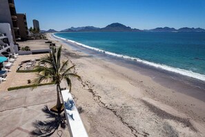 A beachside view with a clear sky, a sandy beach, and a mountain range in the distance. - Mediterranean Scape (San arlos Nuevo Guaymas)