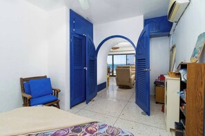 A room with a bed, a chair, a desk, and a view through an open door to a balcony. - Mediterranean Scape (San arlos Nuevo Guaymas)