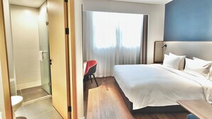A hotel room with a bed, bedside table, chair, and a bathroom with a toilet and shower. - Holiday Inn Express Xi'an Qujiang Center (Xi'an)