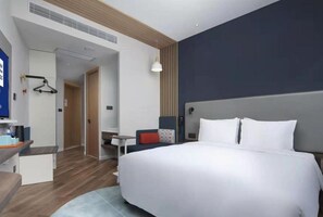 Une chambre d’hôtel moderne équipée d’un grand lit, d’un bureau, d’une chaise et d’une armoire.