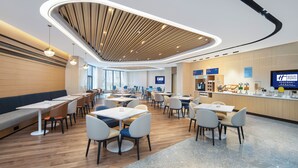A modern hotel lobby with a central seating area, a reception desk, and a large screen displaying the hotel name. - Holiday Inn Express Xi'an Qujiang Center (Xi'an)