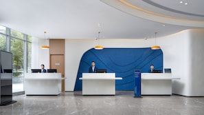 A modern reception area with two receptionists, a blue accent wall, and a clean, polished floor. - Holiday Inn Express Xi'an Qujiang Center (Xi'an)