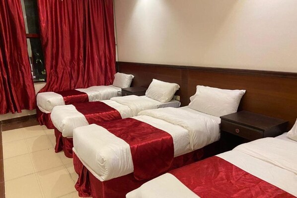 A hotel room with four single beds arranged in a row, each with a red and white bedspread. - Cent Al Khair Hotel Makkah (Makkah)