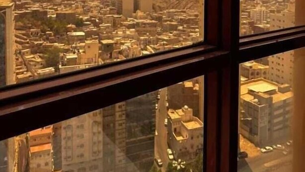 Une vue sur un paysage urbain à travers une fenêtre, avec un bâtiment visible au loin.