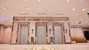 Un hall d’entrée avec trois ascenseurs, une moquette à motifs et un canapé.