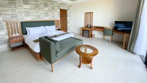 Ein modernes Hotelzimmer mit einem großen Bett, einem Schreibtisch, einem Fernseher und einem kleinen runden Tisch.
