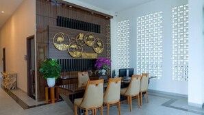 A modern dining area with a wooden table, four chairs, and decorative wall art. - Flamingo Waecicu Labuan Bajo (Labuan Bajo)