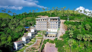A multi-story hotel with a pool and lush greenery surrounding it.