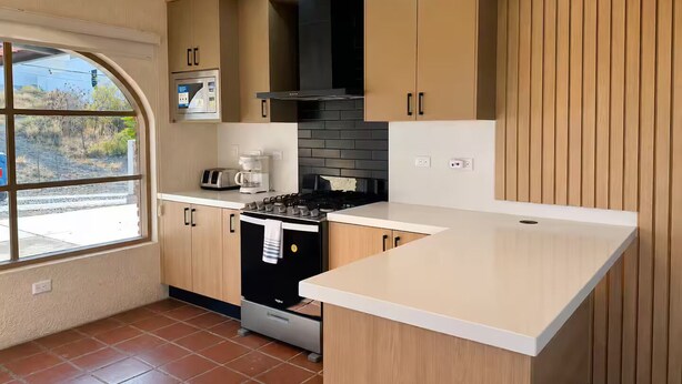 Uma cozinha moderna com ilha central, eletrodomésticos embutidos e uma janela grande.