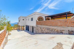 A modern building with a white facade, a brick wall, and a covered area with a red roof. - OMG Ocean Views! | Walk to beach! | Modern kitchen (San Carlos Nuevo Guaymas)