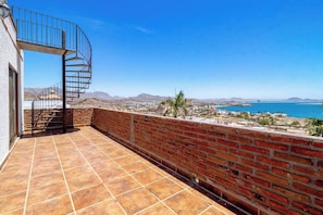 A rooftop terrace with a spiral staircase, a brick wall, and a view of the coastline and mountains. - OMG Ocean Views! | Walk to beach! | Modern kitchen (San Carlos Nuevo Guaymas)