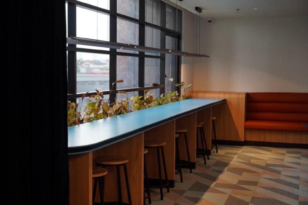 A bar area with a long counter, stools, and a view through large windows.